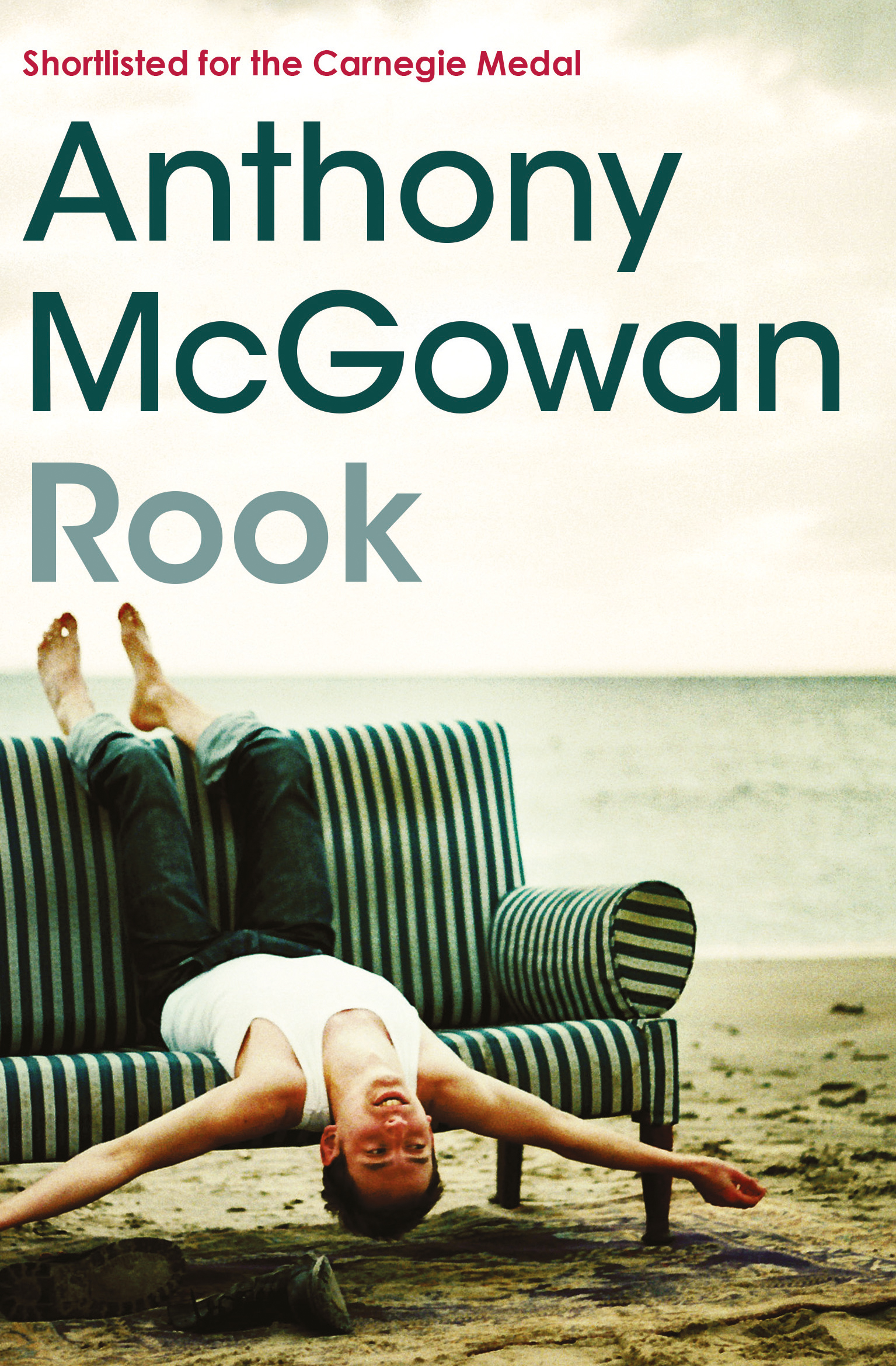 Book jacket for Anthony McGowan, 'Rook'. Cover image is a photograph of a teenage boy splayed upside down on a sofa placed on the beach.